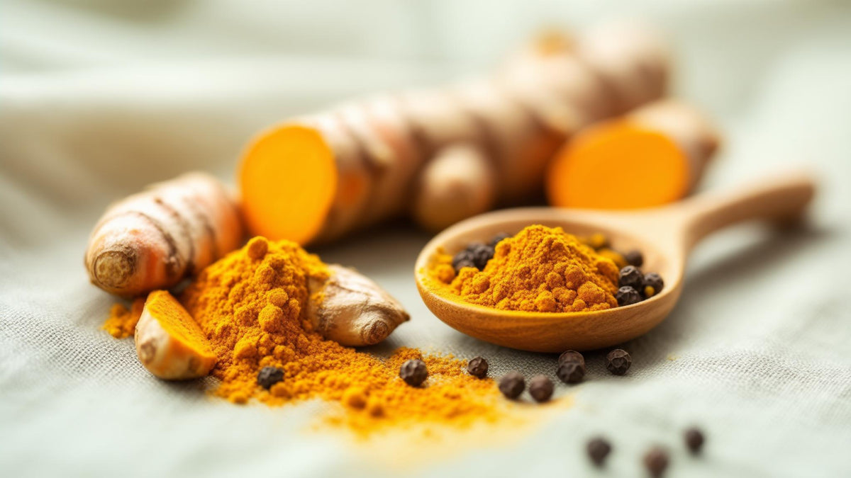 Sliced turmeric root, ground turmeric on a wooden spoon and black peppercorns on linen
