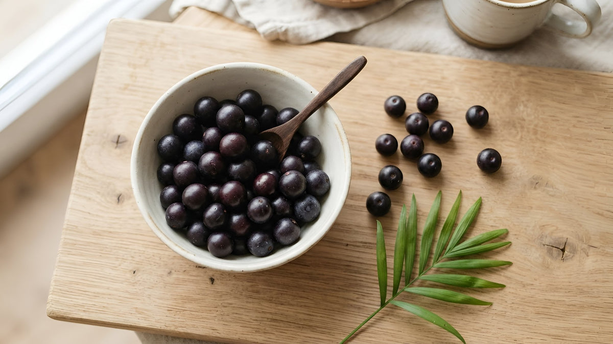Bowl of dark purple acai berries on a light oak board