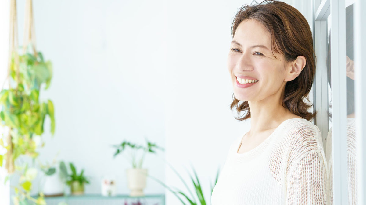 Calm middle-aged woman sitting by a bright window at home