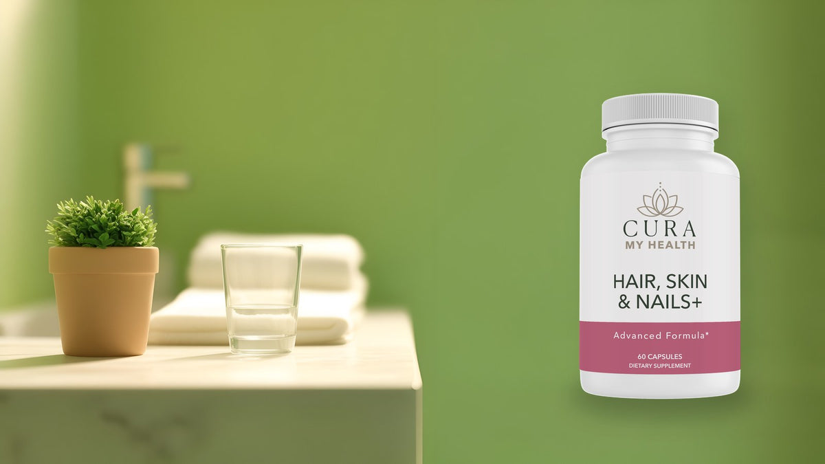Hair, Skin & Nails+ by CuraMyHealth on a bathroom vanity shelf beside a towel and a glass of water