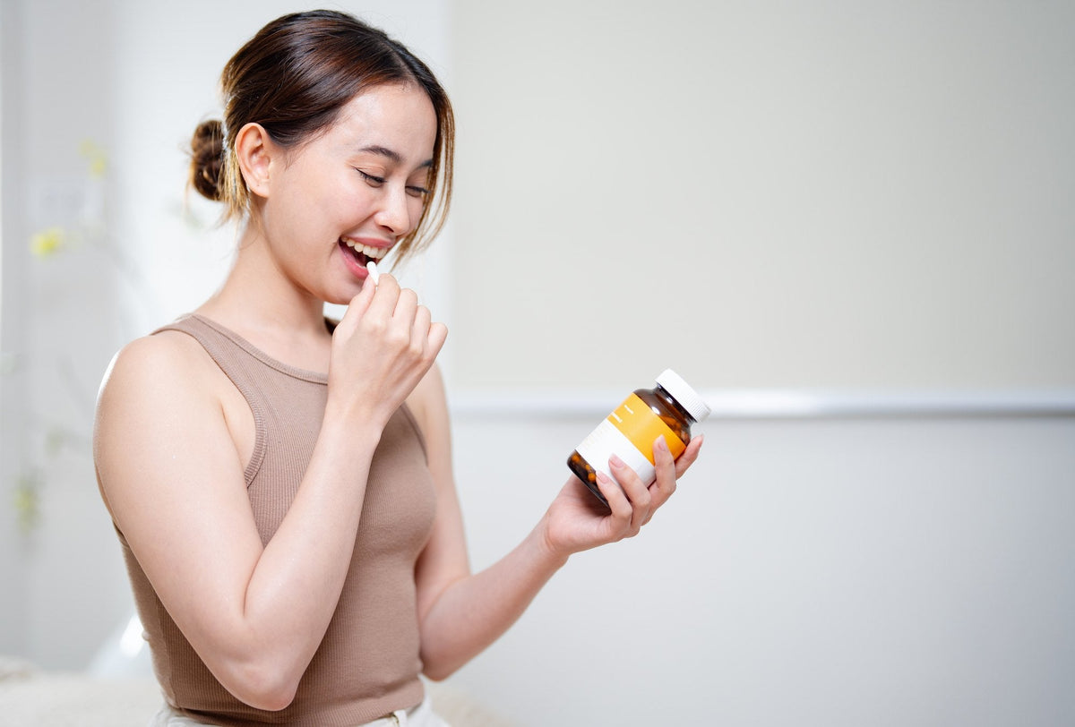 Woman taking a supplement capsule from a bottle as part of her evening wind-down routine