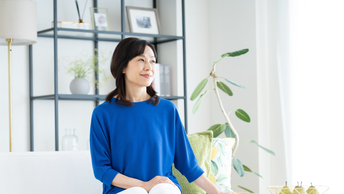 A person sitting calmly on a white sofa in a bright, minimal living room
