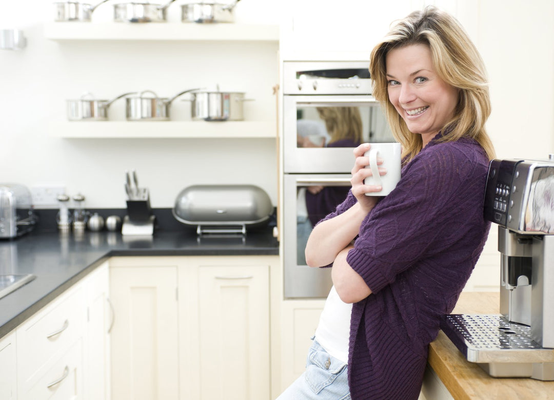 A calm, content woman with a warm mug in her kitchen
