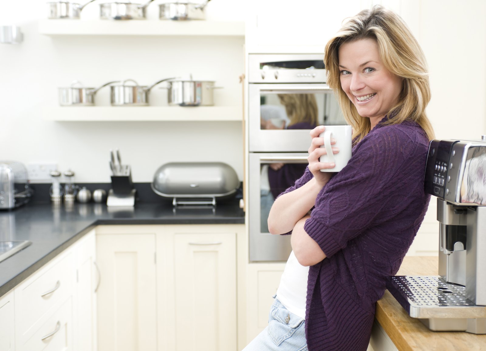 A calm, content woman with a warm mug in her kitchen