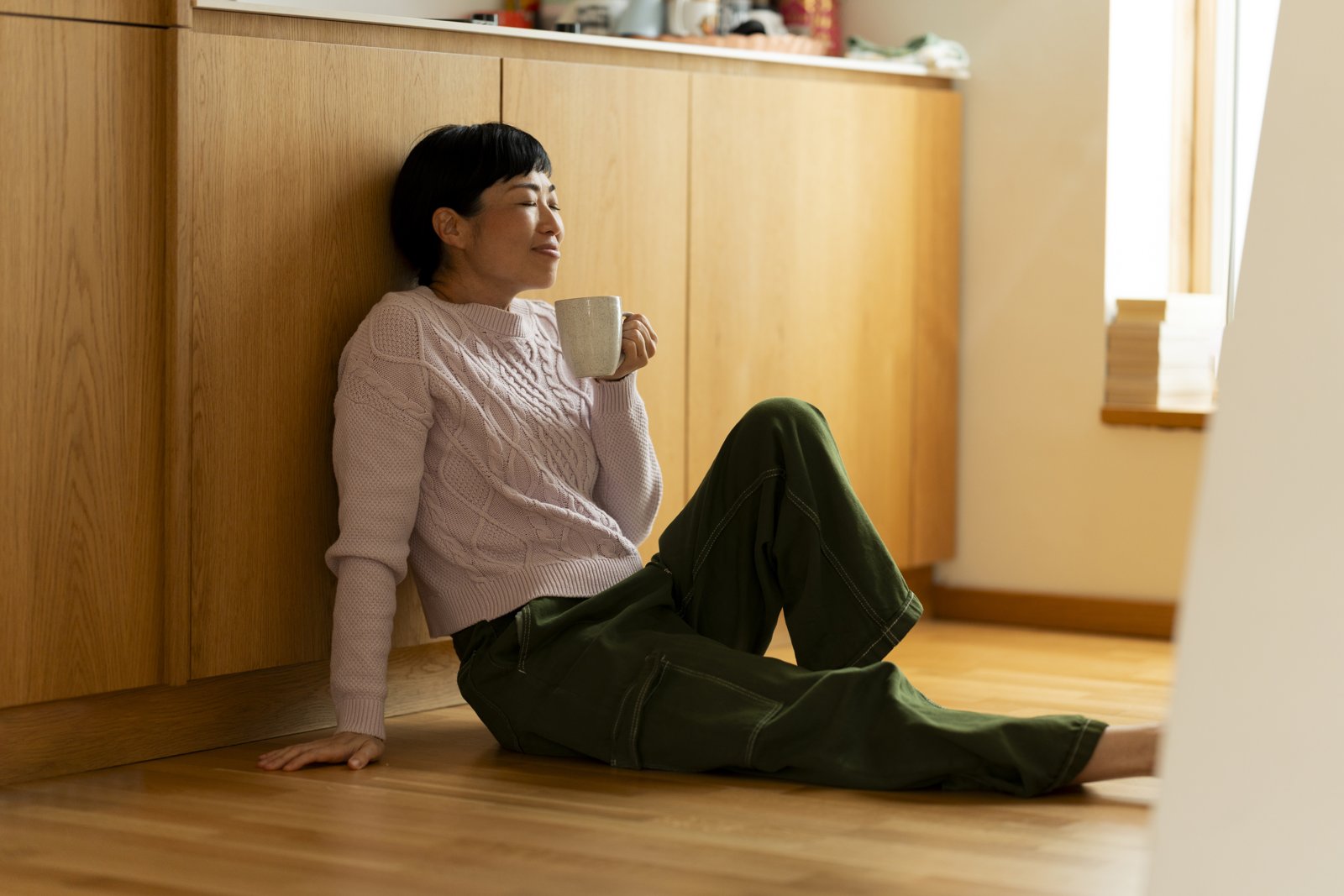 A woman pausing with a warm cup of tea — a calm evening wind-down