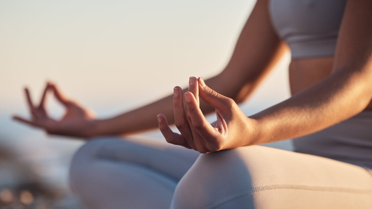 Close-up of hands resting in a meditation pose outdoors at sunset